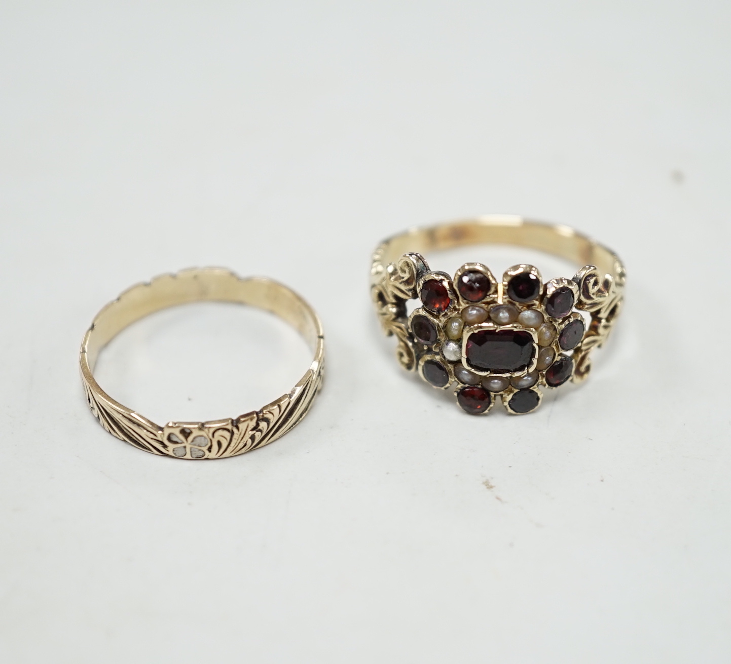 An early 19th century yellow metal, garnet and seed pearl cluster set ring, size P and a 19th century yellow metal and two colour enamel set band.